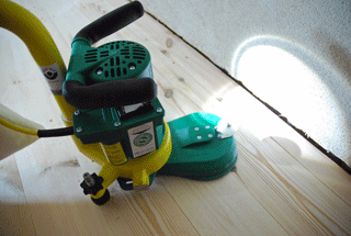 Eine kleine Randschleifmaschine mit Beleuchtung auf einem Dielenboden.