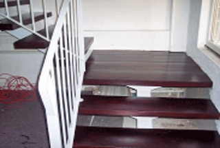 Das Bild zeigt eine eingefärbte Treppe in Mahagonie. Das Treppengeländer ist aus Metall und weiß lackiert.